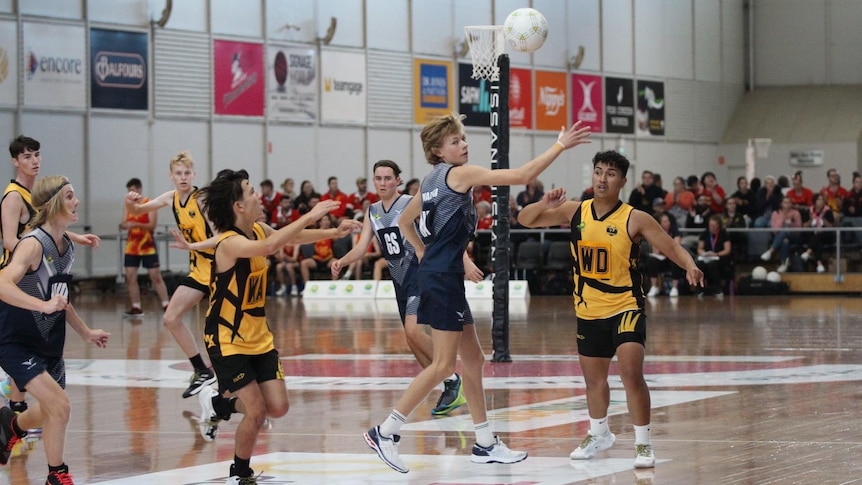 Ball is in the air above Zac his teammates and opposition watching with their arms up 