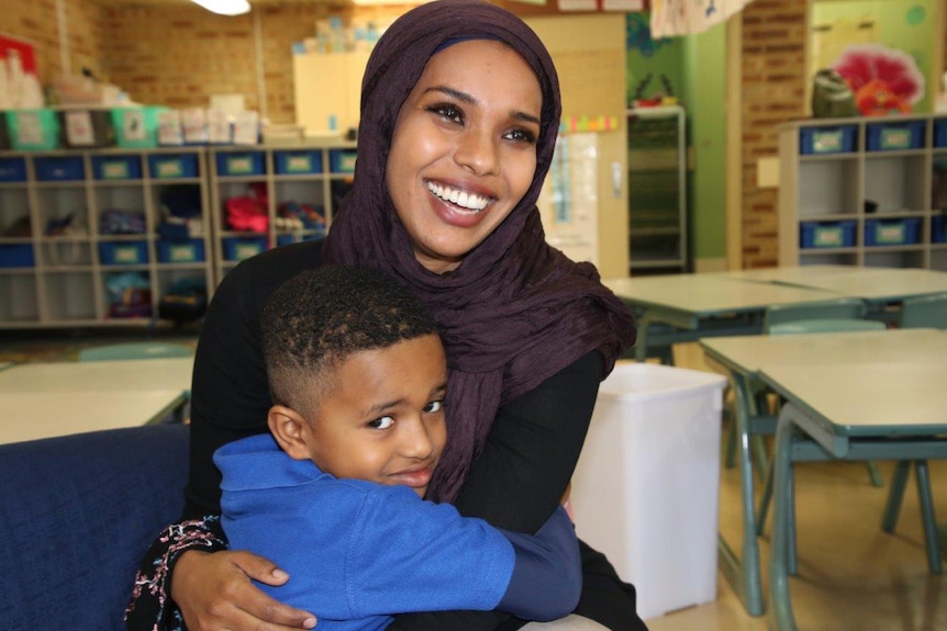 Hussain Hussain sits in a classroom hugging his smiling mother.