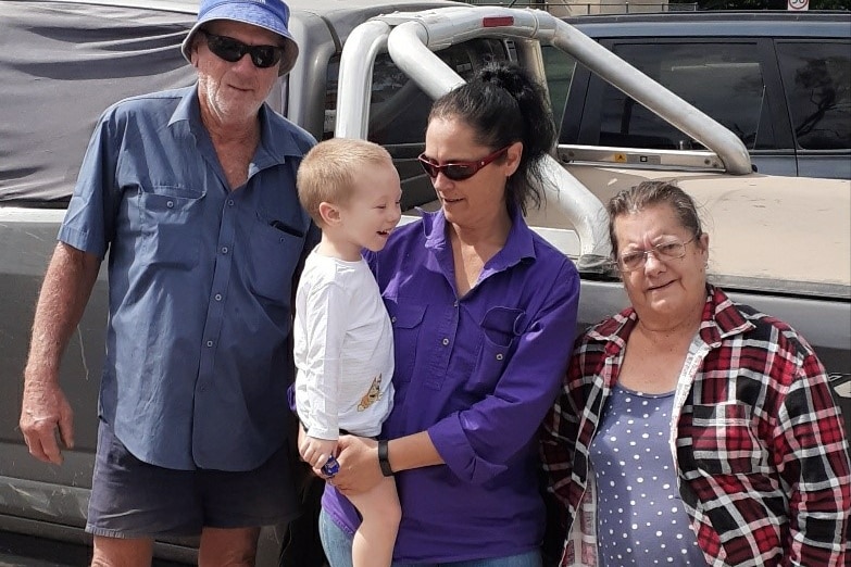  A family of four people, with a young boy being held by his mother