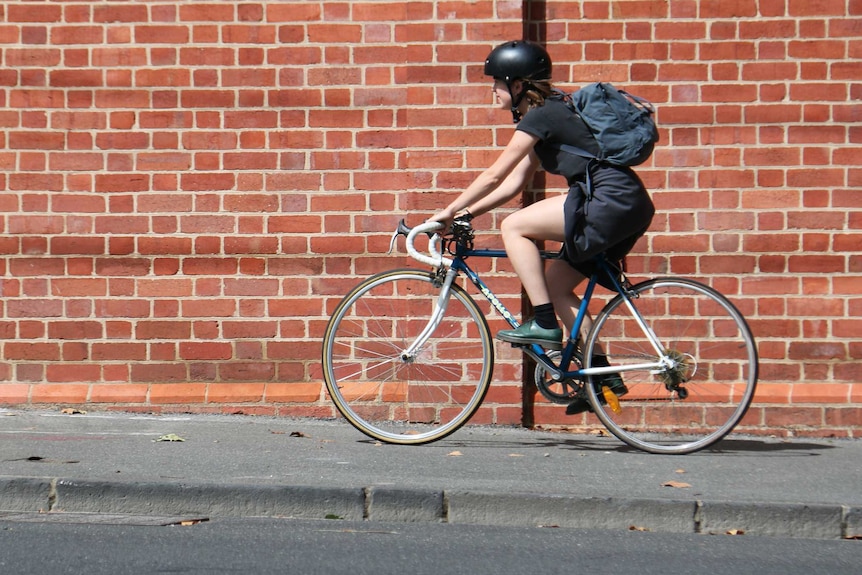 A cyclist rides down the footpath