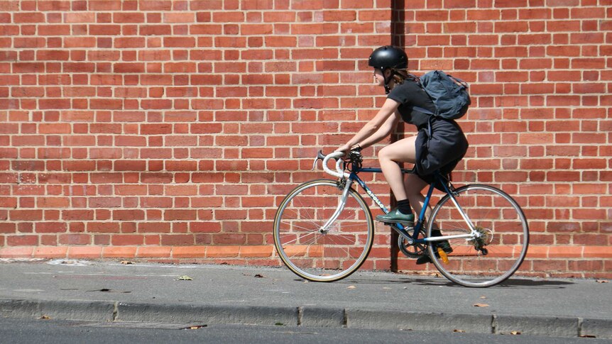 A cyclist rides down the footpath