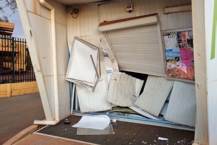 The garage door protecting a shop front is left in ruins after a ram raid.