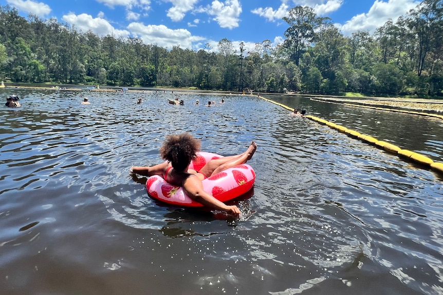 Yasmin is seen floating on Enoggera dam with her back to the camera while in a donut with strawberries on it.