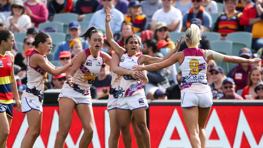 Brisbane players celebrate a goal on the AFL field