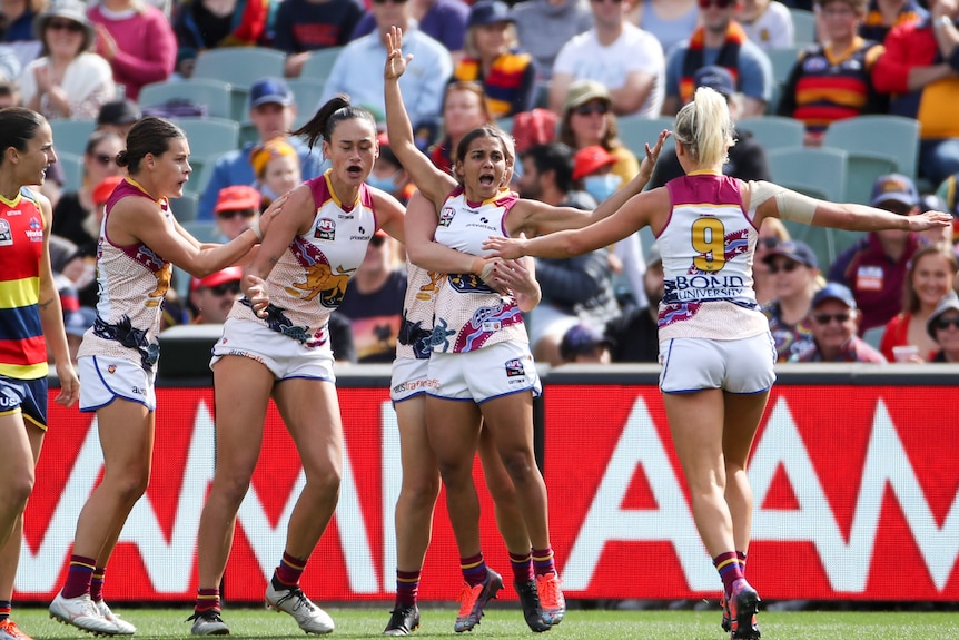 Brisbane players celebrate a goal on the AFL field