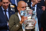A male football manager kisses the FA Cup following Manchester City's victory in the final.