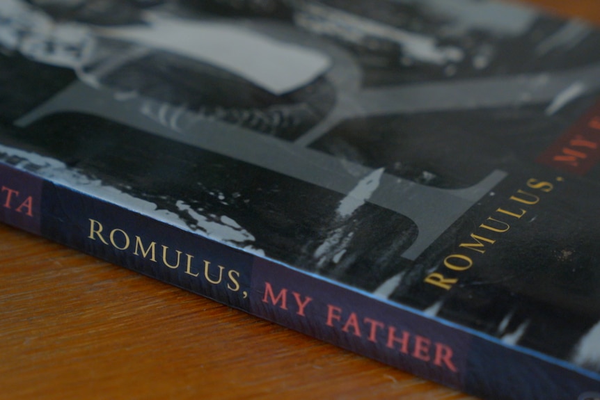 Raimond Gaita's book, Romulus, My Father sits on a brown table with part of the black and white cover and purple spine visible.