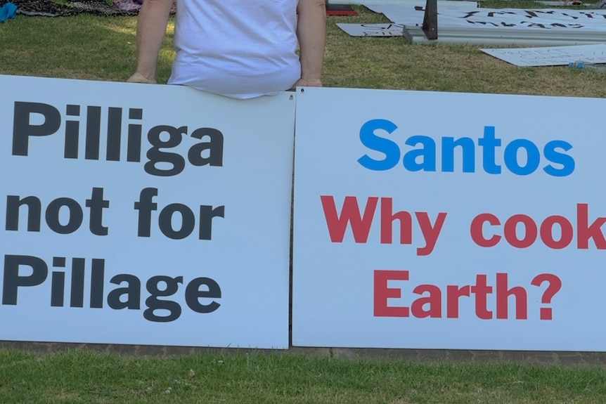Posters at the protest saying 'Pilliga not for pillage' and 'Santos why cook earth'