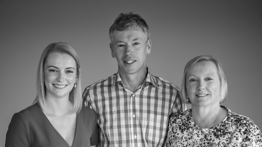 Black and white photo of a smiling mother, father and daughter.