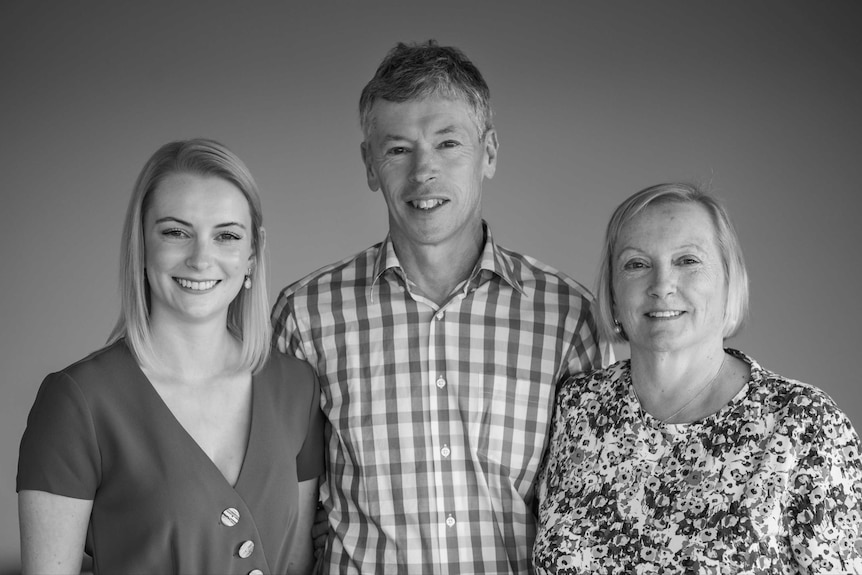 Black and white photo of a smiling mother, father and daughter.