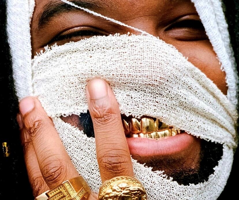 Album cover featuring a man with bandages on his face and gold teeth