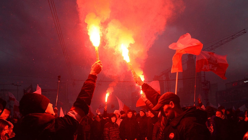 Demonstrators burn flares and wave Polish flags during a far-right march in Warsaw.