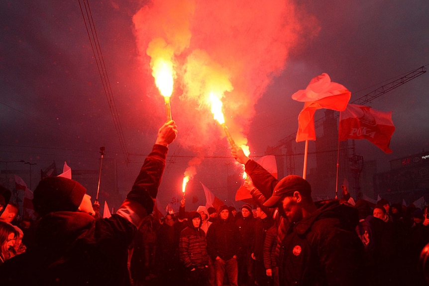 Demonstrators burn flares and wave Polish flags during a far-right march in Warsaw.