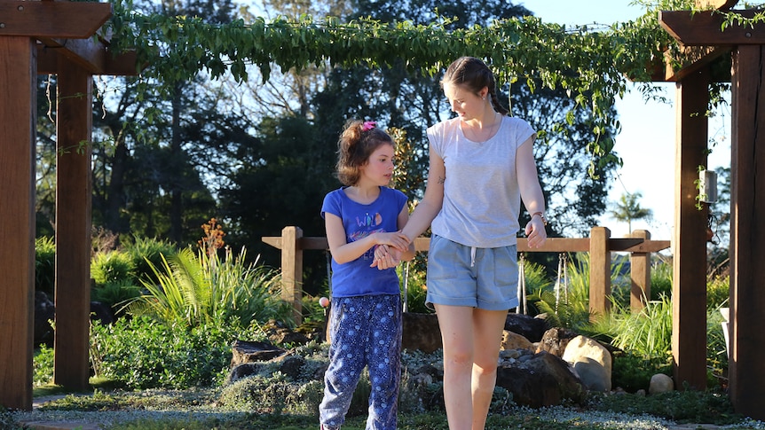 Riley Steer and Georgette walking through garden holding hands