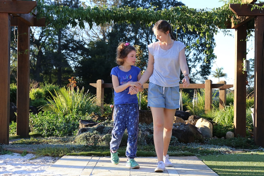 Riley Steer and Georgette walking through garden holding hands
