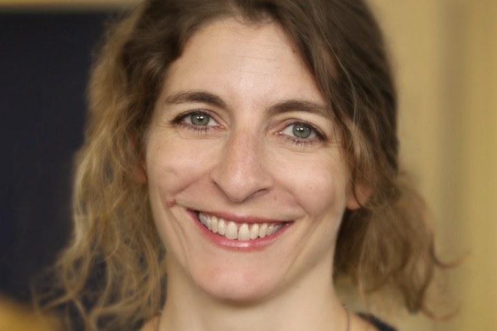 A close-up portrait of a woman smiling at the camera.