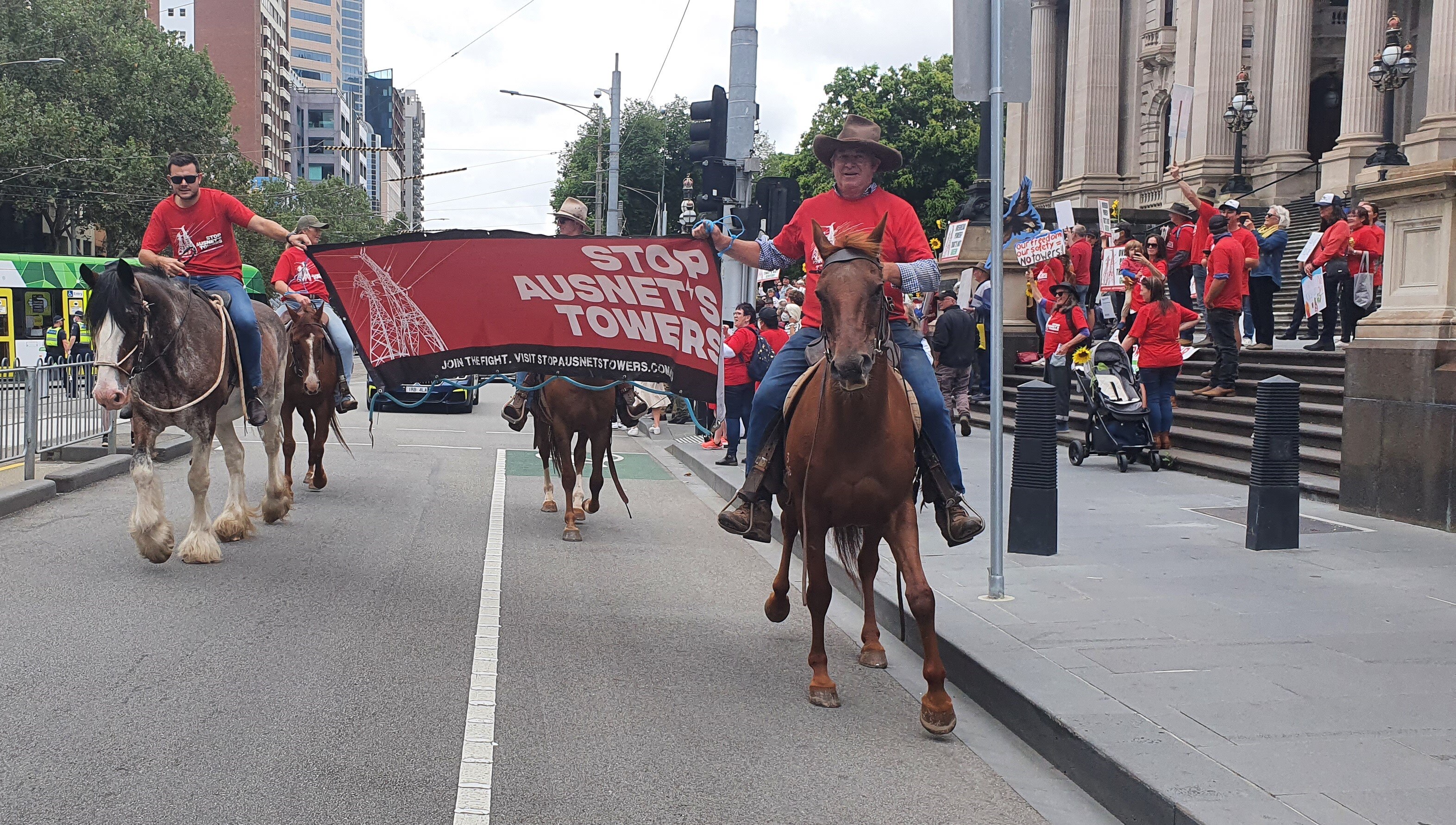 People holding banners ride horses down a city street.