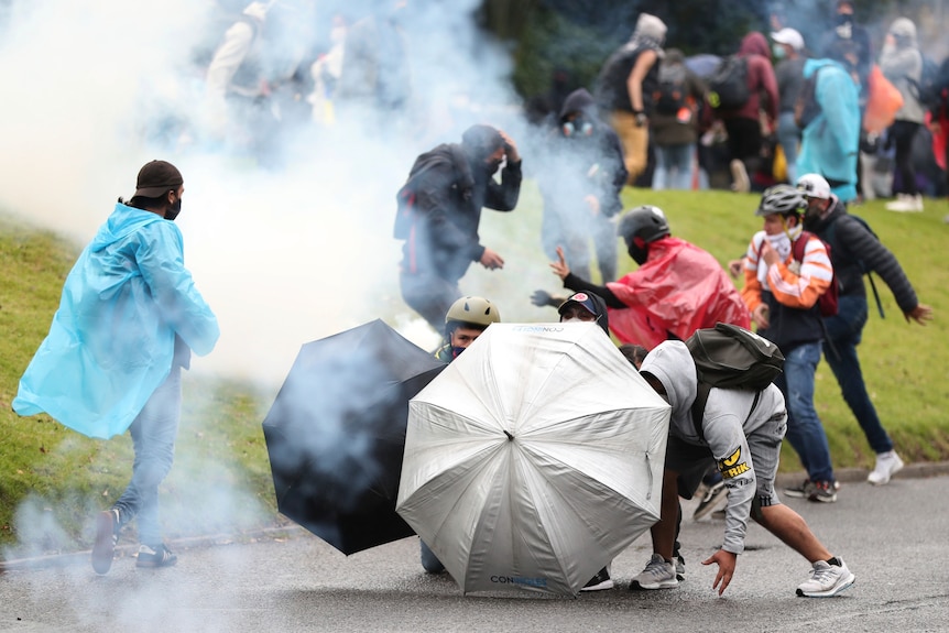 Protesters use umbrellas as shields against tear gas launched by police.