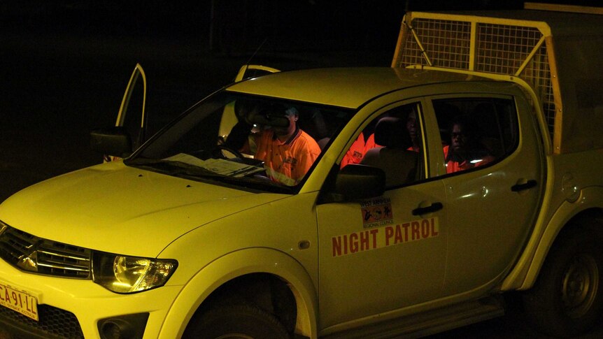 A group of people in orange official jackets in a car.