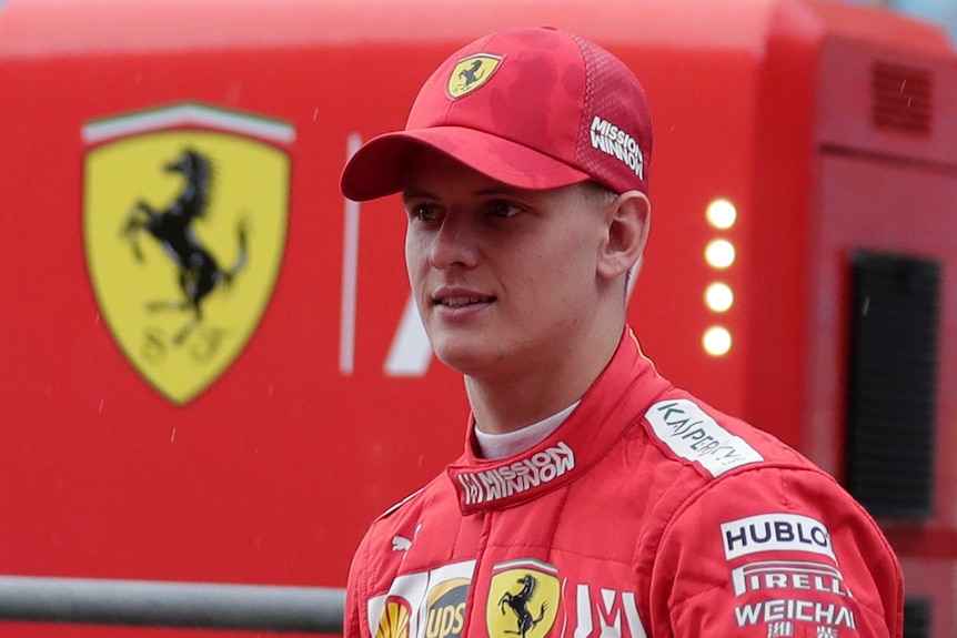 The son of F1 legend Michael Schumacher is pictured in pit lane wearing his Ferrari gear and hat.