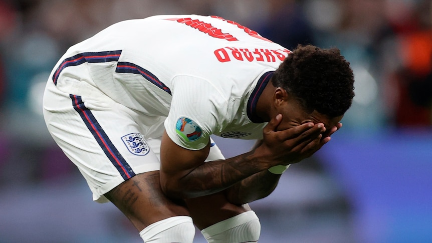 Marcus Rashford bends over and covers his face with his hands