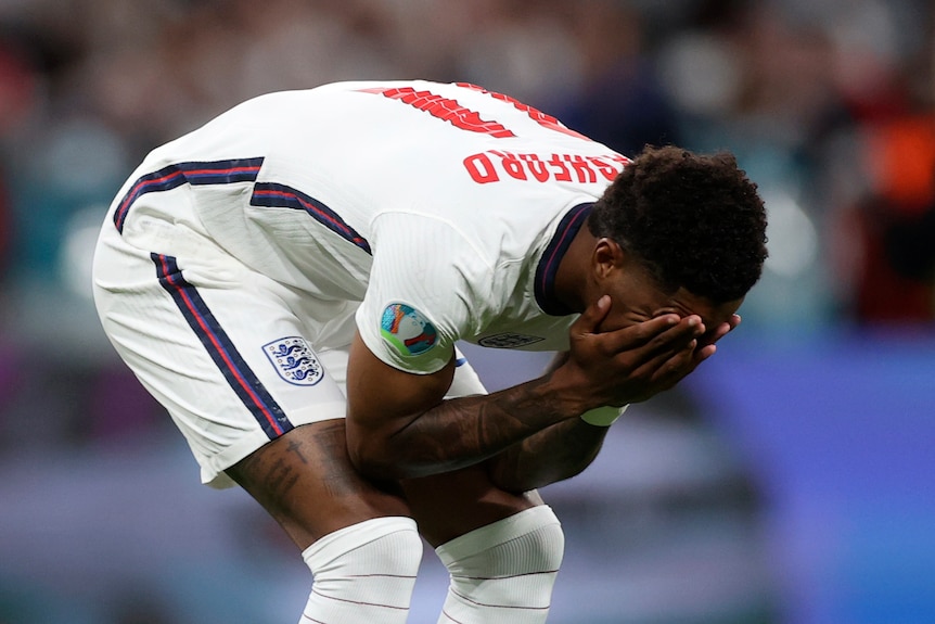 Marcus Rashford bends over and covers his face with his hands