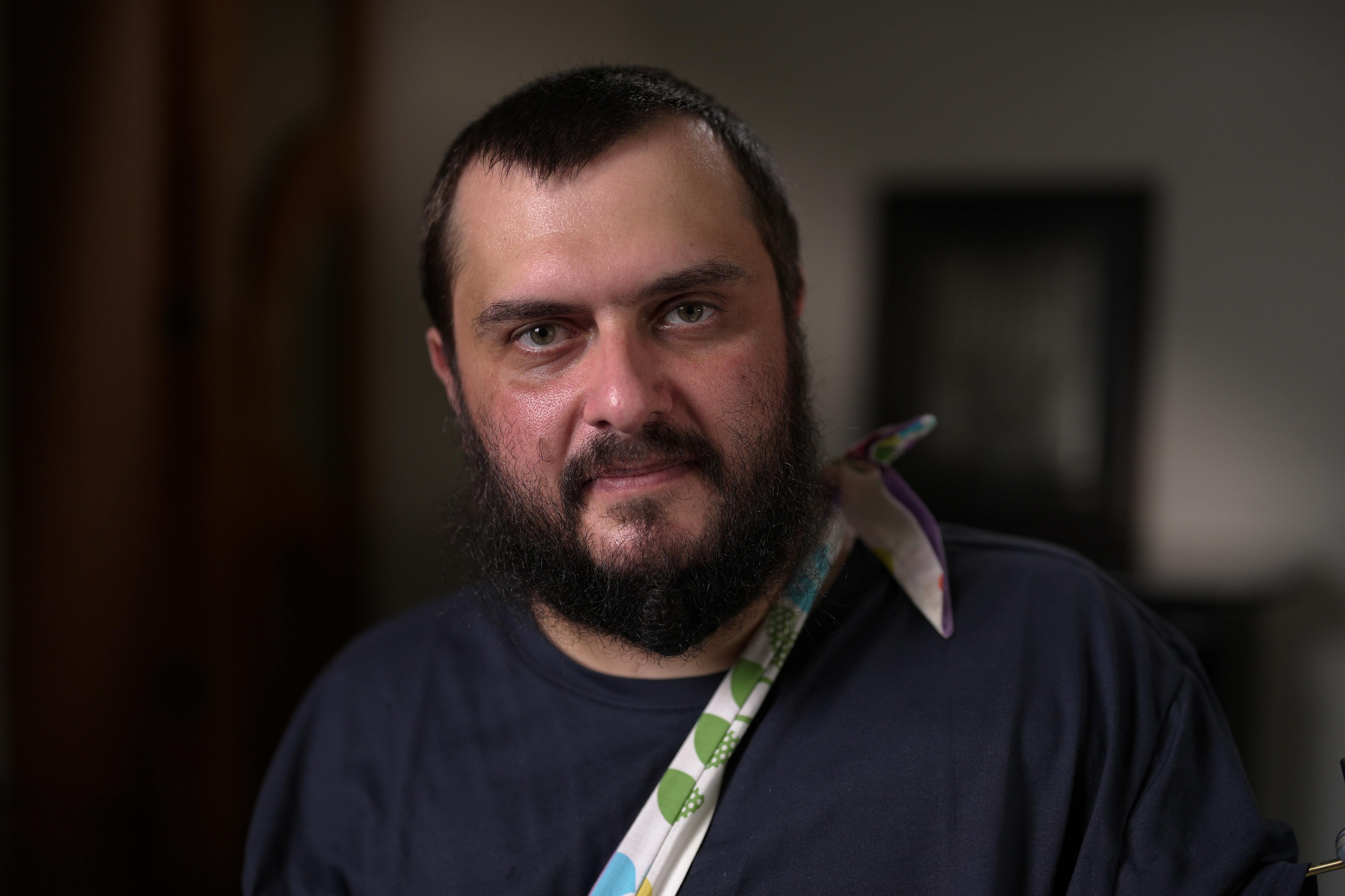 Um homem com o braço na tipóia olha para frente.