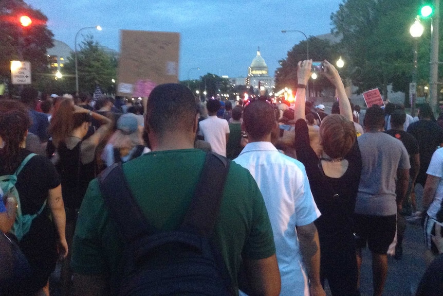 A crowd of people walks up the street.