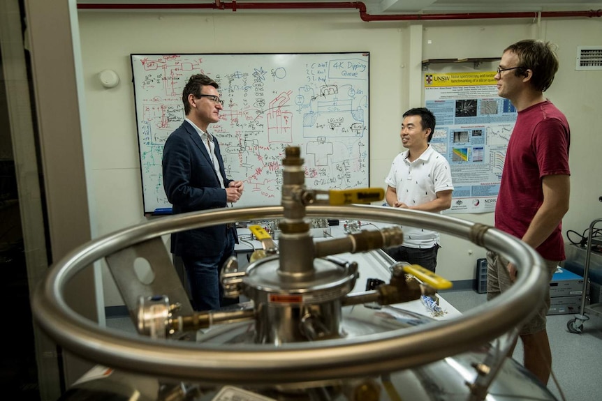 Scientists stand in a quantum measurement lab at UNSW in front a white board covered in mathematic equations