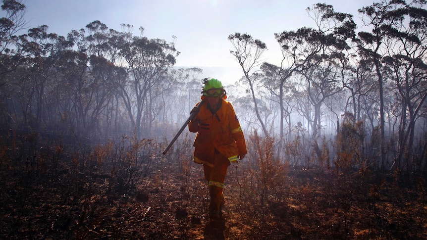 A female rural fire service firefighter walks through Blackheath