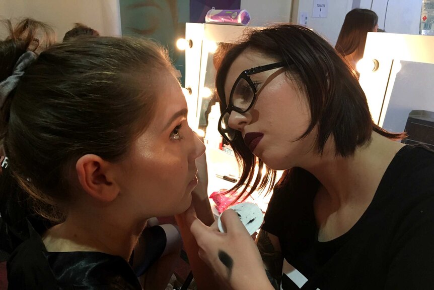 A makeup artist works with a model.