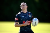 Rugby league player Dylan Edwards during a NSW Blues training session, holding a ball and lightly jogging