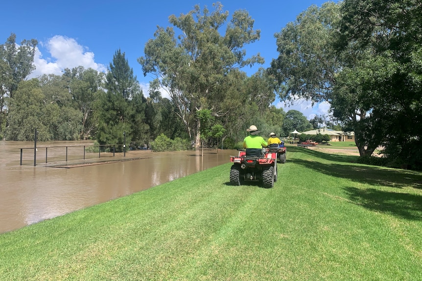 Two quad bikes ride along the top of a levee bank