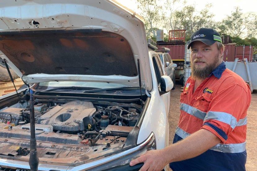 A man stands next to a car with the bonnet open