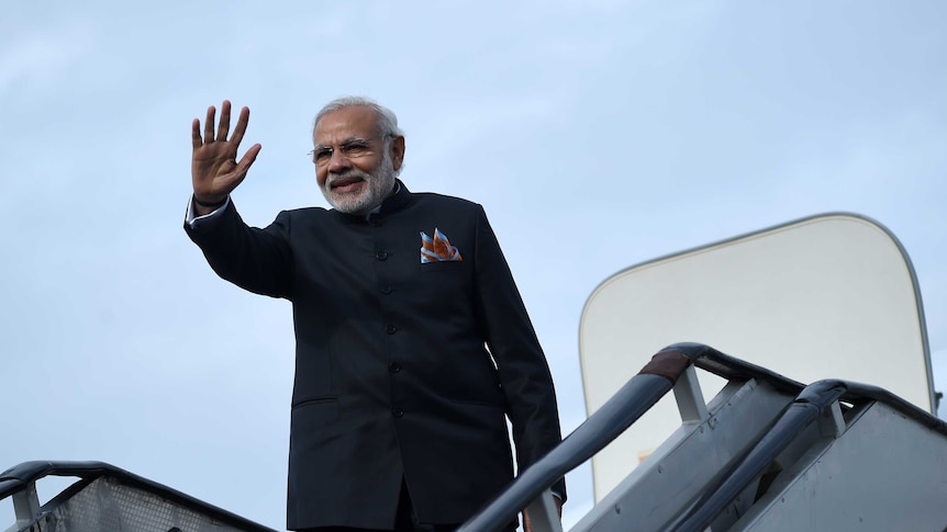 Narendra Modi raises his hand as he boards an aircraft.