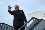 Narendra Modi raises his hand as he boards an aircraft.