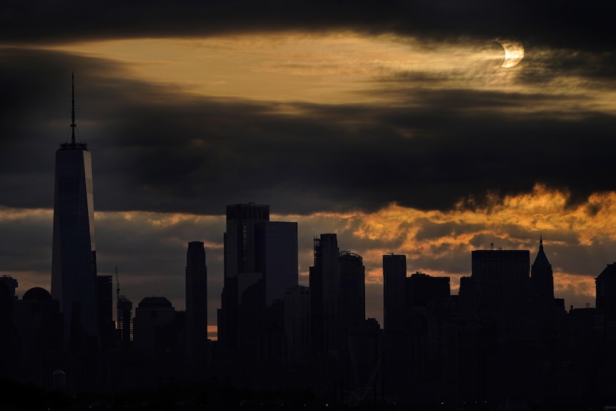The sun is partially eclipsed as it rises over lower Manhattan in New York