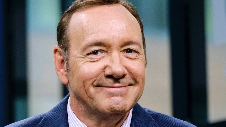 Man in velvet blue suit smiles at the camera