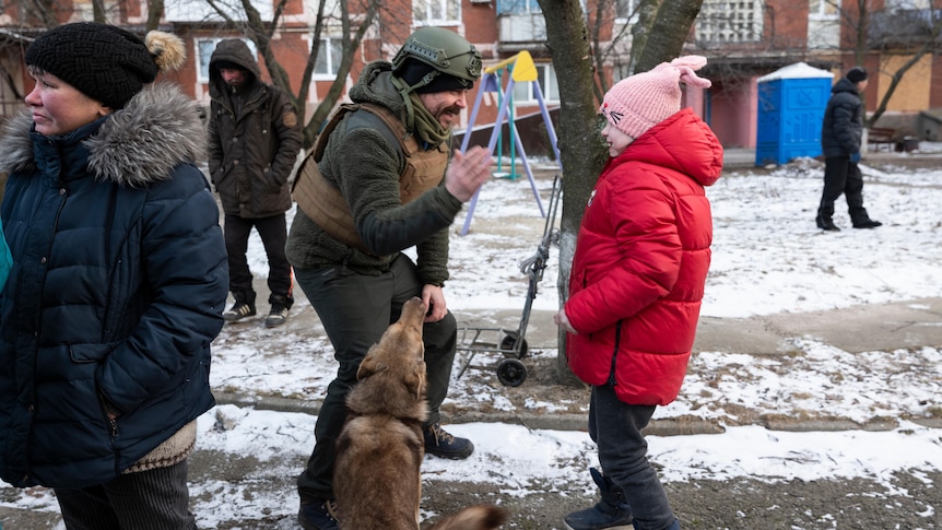 A girl in a red parka and pink beanie gives a high five to a man in combat fatigues