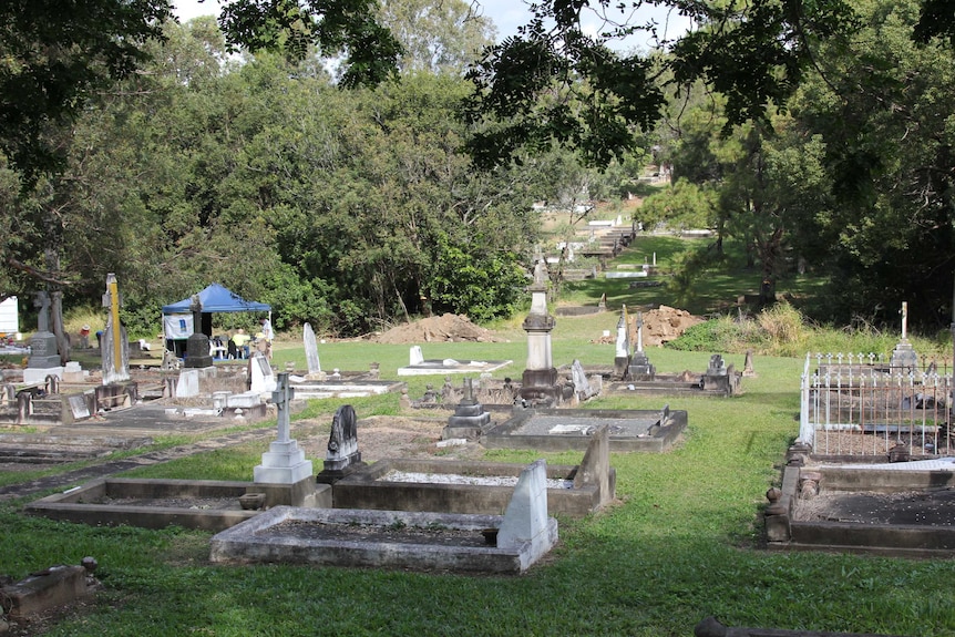 Old cemetery with a blue shade tent and a pile of dirt