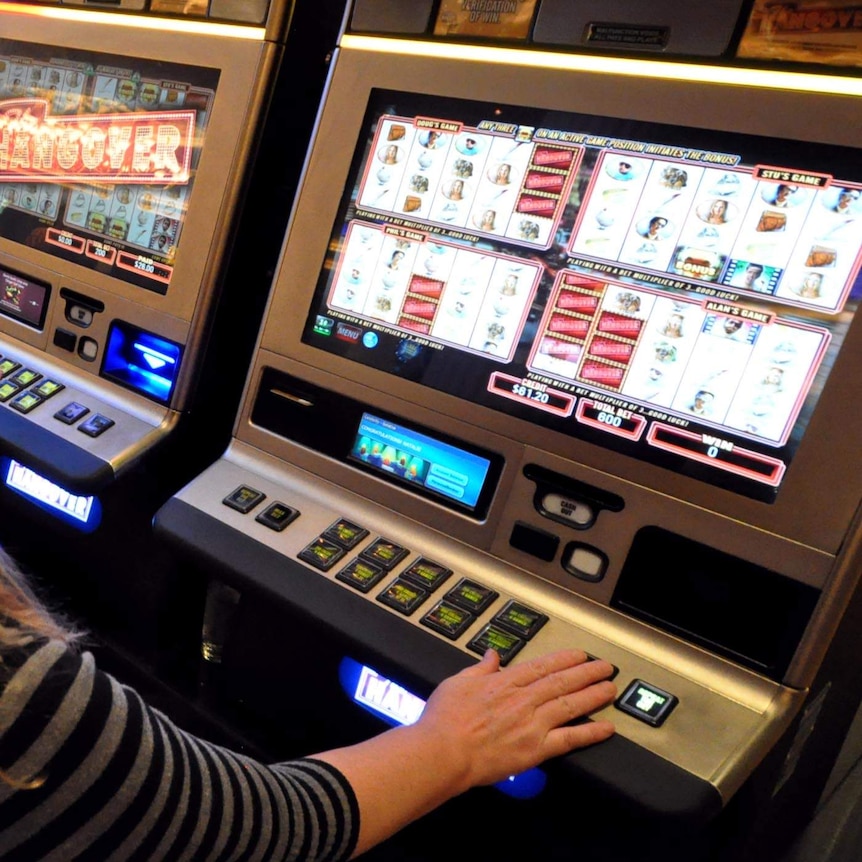 A woman plays a poker machine.