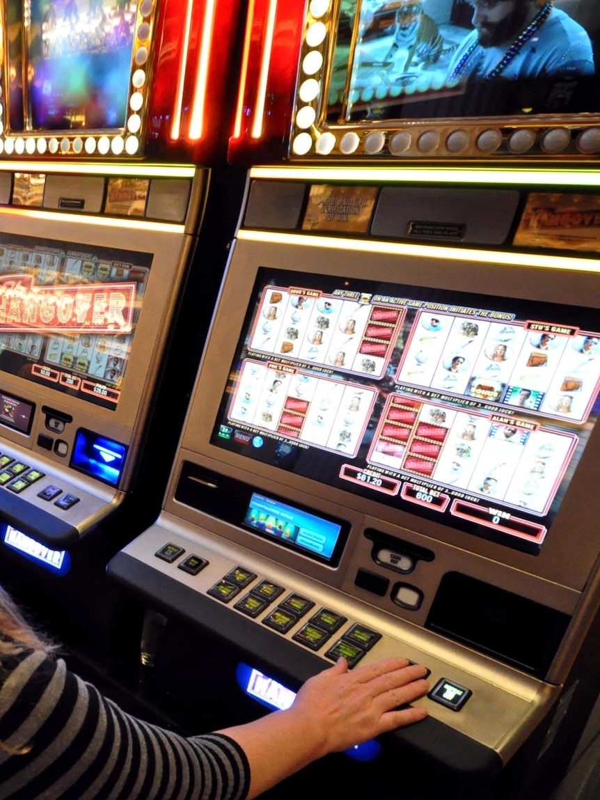 A woman plays a poker machine.