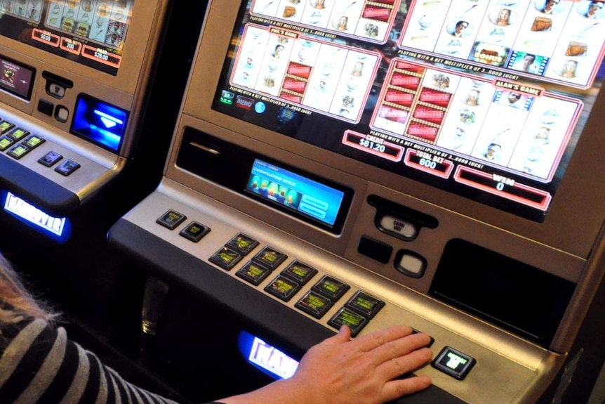 A woman plays a poker machine.