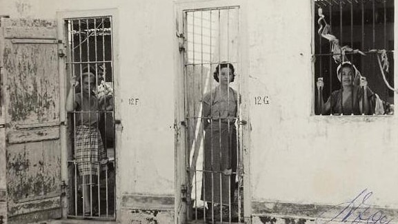 Women standing behind bars in a concentration camp in Indonesia in 1945.