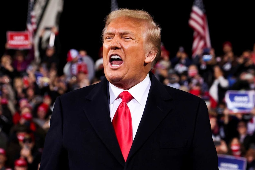 US President Donald Trump reacts as he arrives to attend a campaign rally