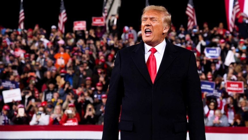 US President Donald Trump reacts as he arrives to attend a campaign rally