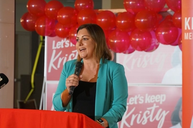 a woman smiles into a microphone