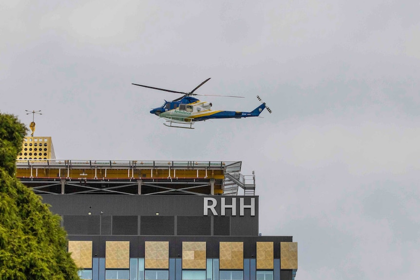 An ambulance helicopter flies overhead a hospital building.