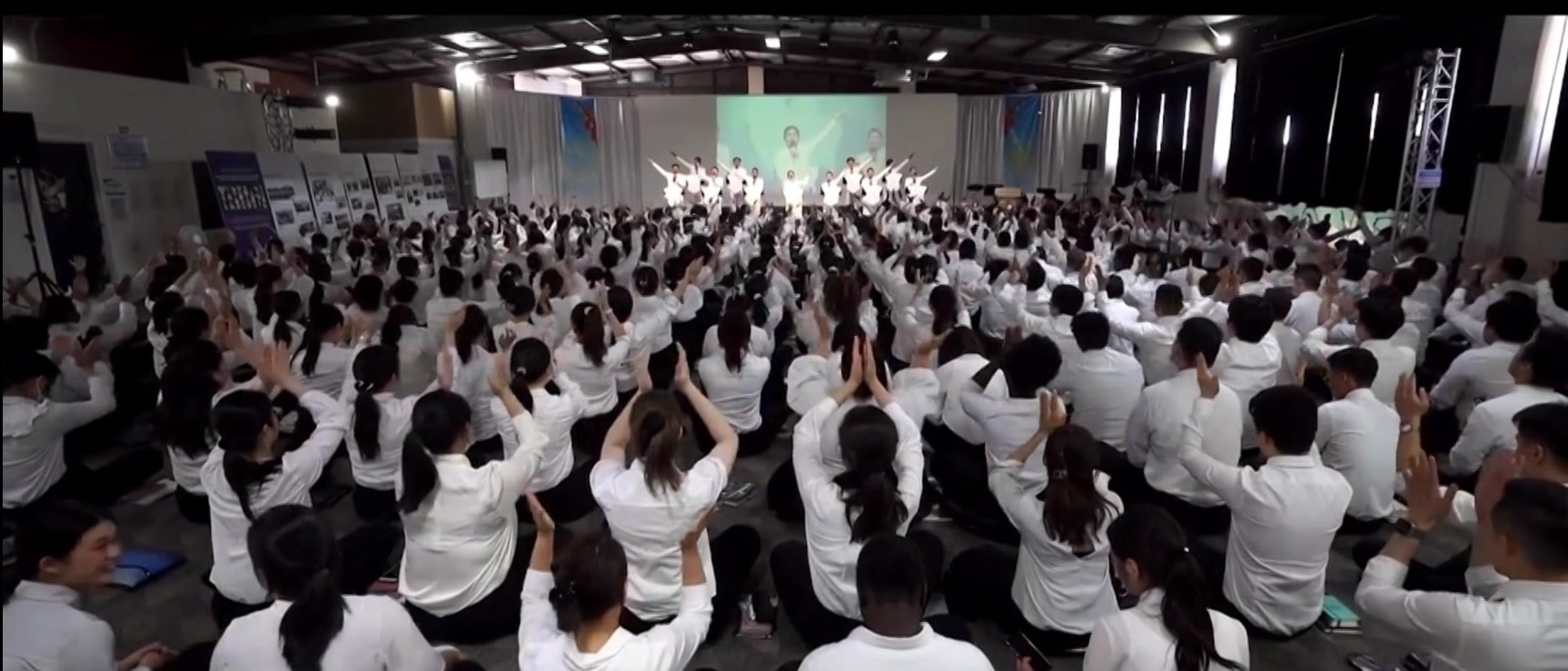 Um grande grupo de pessoas assistindo a uma apresentação religiosa.