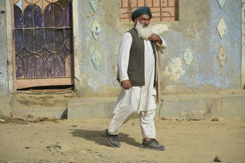 A man walks along a dirt road in Pakistan.